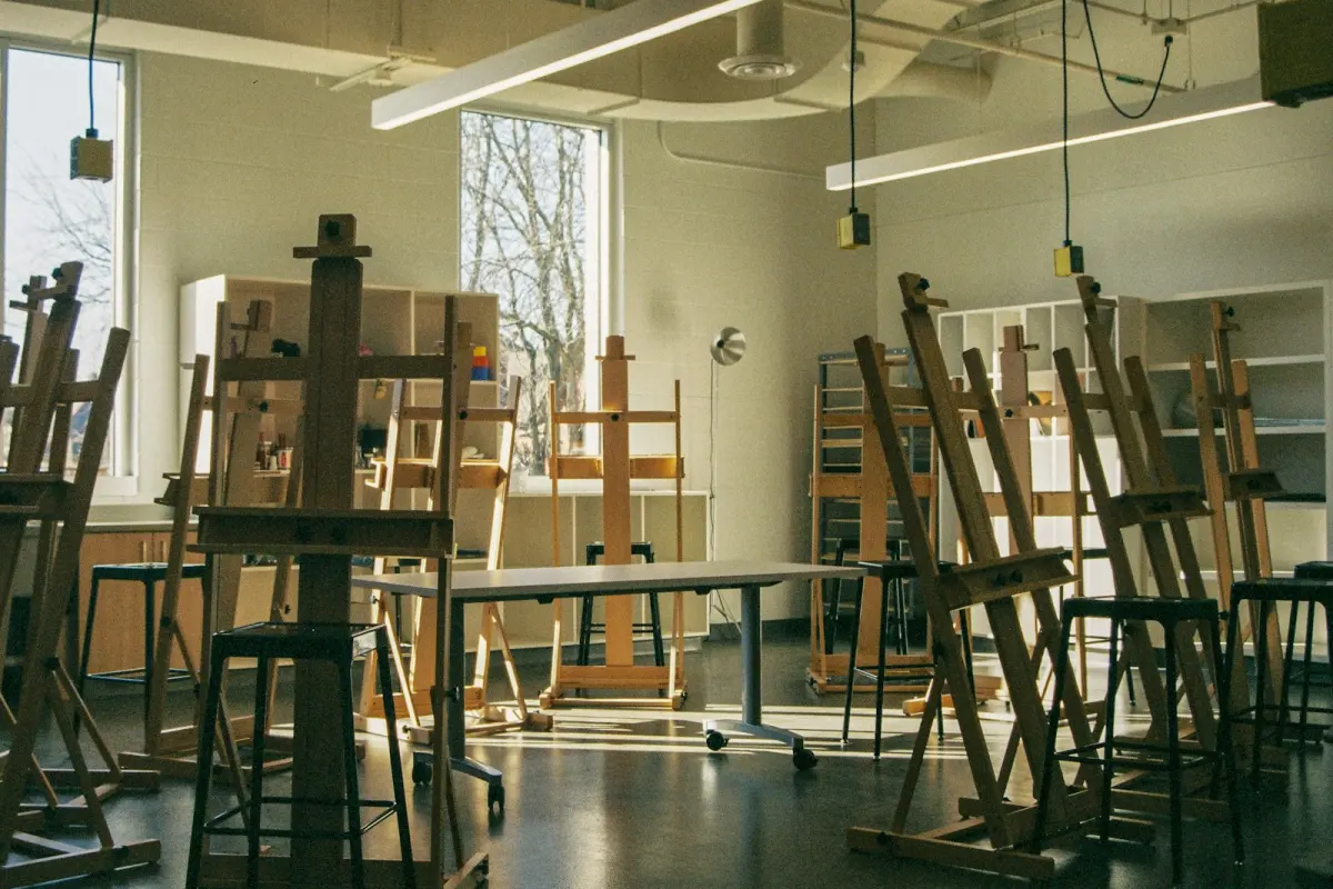 Sanat akademisi aydınlık atölyesinde şövale başında resim yapan sanat öğrencisi